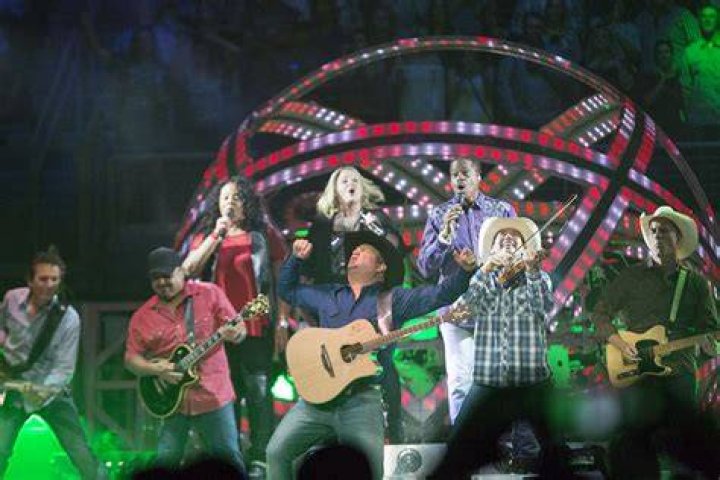 Garth Brooks received his 7th Diamond Certificate from the RIAA in 2016. Pink shirt and thowing his hands up in the air.